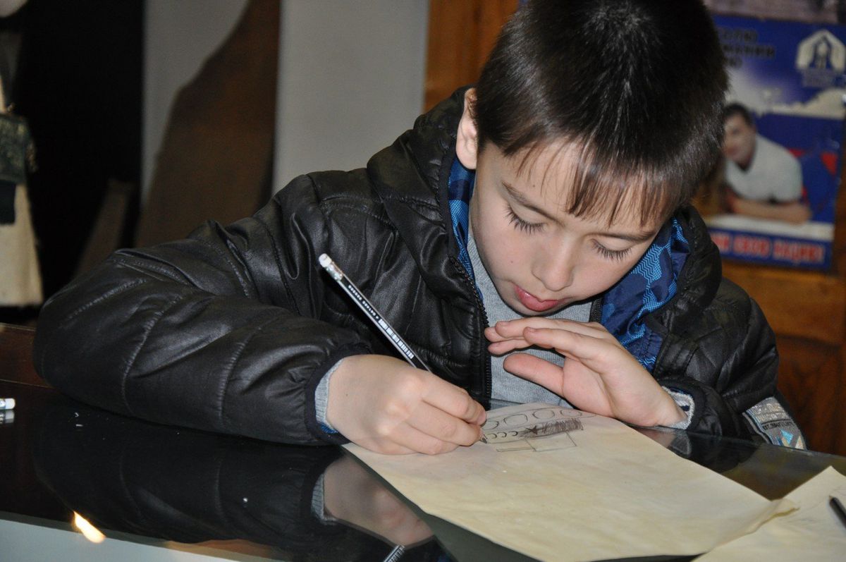 Мастер-класс "Солдатские письма-треугольники" в музее. Мальчик пишет письмо...