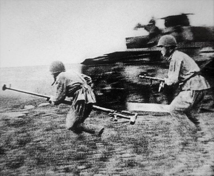 Бронебойщики Красной Армии с противотанковым ружьем ПТРД-41 бегут мимо немецкого танка  Pz.Kpfw. III во время боев на Курской дуге.